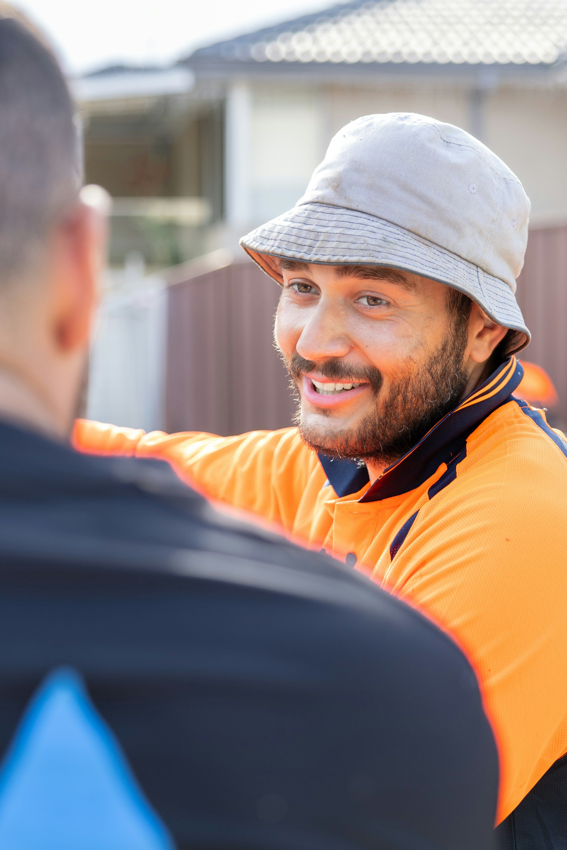 Lachende vakman in oranje werkkleding in gesprek met een collega
